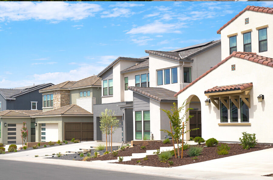 Row of modern suburban houses in Tampa, FL, with varied designs, featuring clean lines and contemporary architecture. The homes are surrounded by landscaped yards and a clear blue sky above.